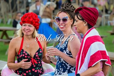 Three women in vintage swimsuits and swim caps enjoying a sunny day outdoors.