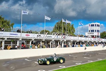 Vintage green race car on track at Goodwood Revival event.