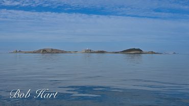 Calm sea with a distant island under a blue sky.