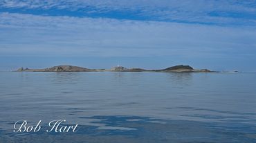 Calm sea with a distant island under a blue sky.