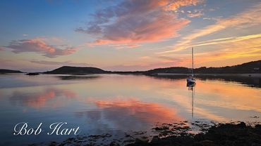 Serene sunset over calm waters with a solitary sailboat.