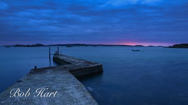 A peaceful jetty stretching into calm blue waters at dawn, Old Grimsby, Tresco, The Scilly Islands, 