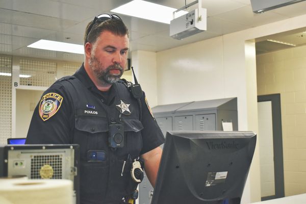 Officer working on Sex Offender Registration at a computer in booking area.