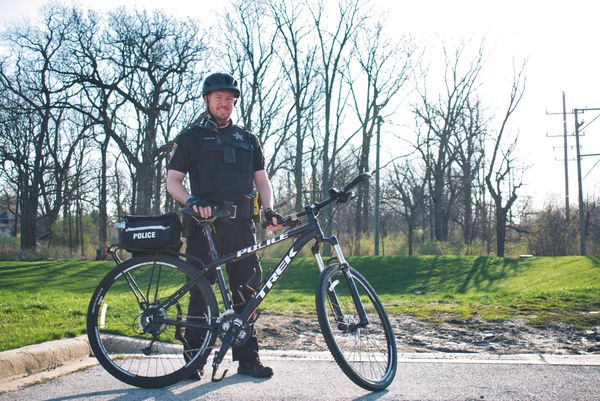 Bike patrol officer standing next to police bicycle.