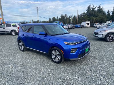 Blue Kia Soul parked on gravel lot.