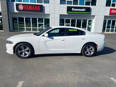 White sedan parked in front of motorcycle brand signs.