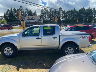 Silver 4x4 pickup truck parked on grass near a fence with other cars.