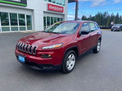 Red 2015 Jeep Cherokee parked outside a dealership on a clear day.