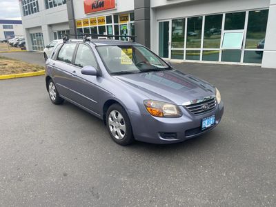 Silver Kia hatchback parked outside dealership.