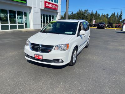 White 2016 Dodge minivan parked outside a dealership.
