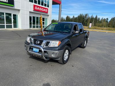 Black 2010 Nissan pickup truck parked outside a dealership.