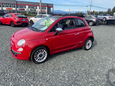 Red compact car parked on gravel lot.