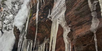 Icicles hanging from a rocky ledge covered in snow.