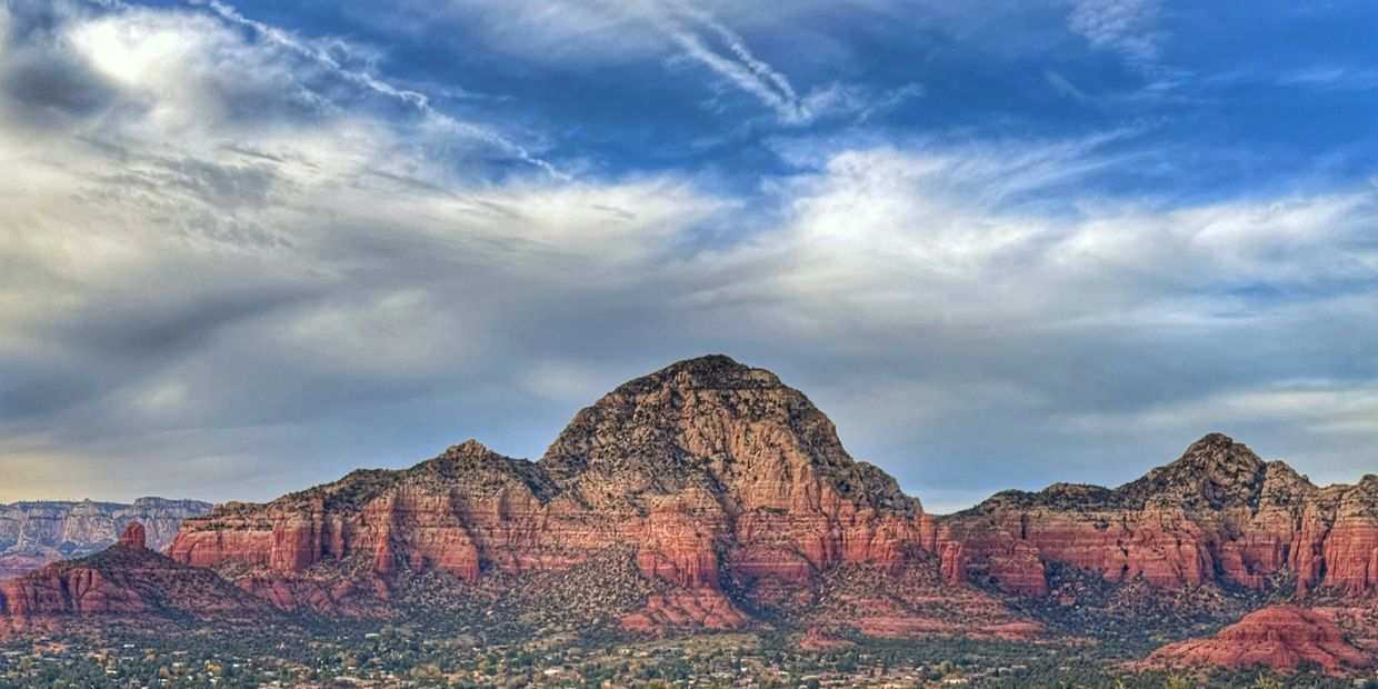 Red rock formations under a partly cloudy blue sky.