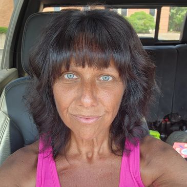 Woman with blue eyes and dark hair sits in a car.