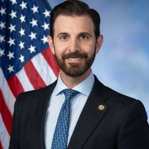 Man in suit with American flag background.