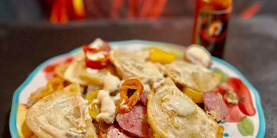 Plate of nachos topped with melted cheese, jalapeños, and slices of sausage.