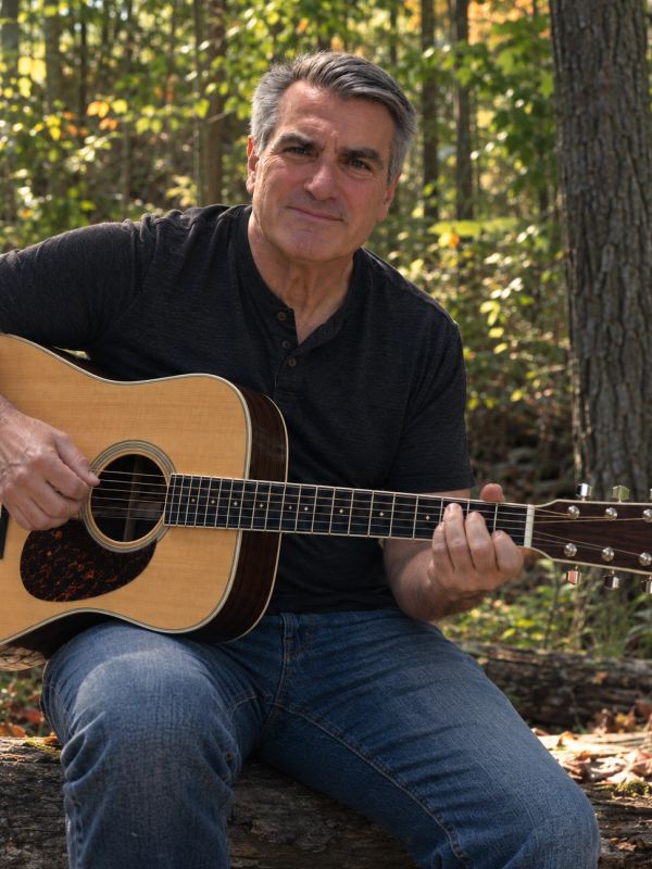 Man playing acoustic guitar outdoors.