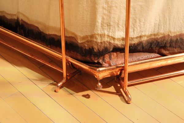 Copper bed frame with wooden floor beneath.
