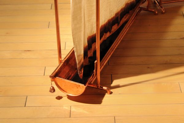 Copper clothes dryer with drying fabric on wooden floor.