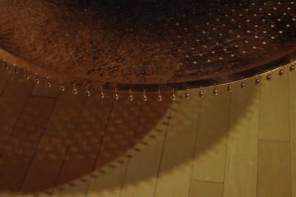 Close-up of a gong with small beads hanging around its edge.