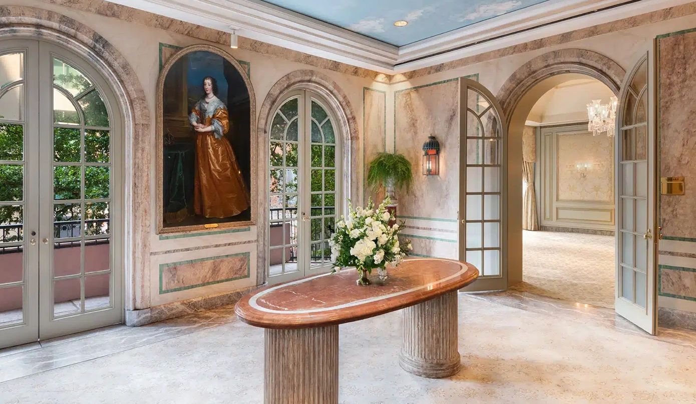 Elegant room with arched doors, marble table, and a classical portrait.