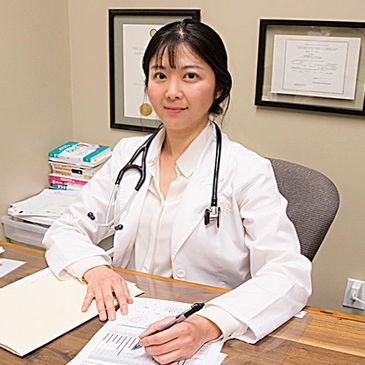 Female doctor in white coat sitting at desk with medical documents.