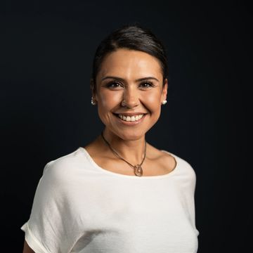 Frau lächelt vor schwarzem Hintergrund.
