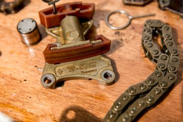 Vintage metal tool and chain on wooden table.