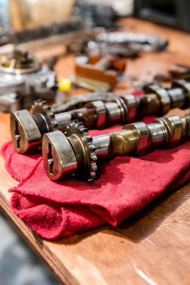 Two metal camshafts resting on a red cloth.