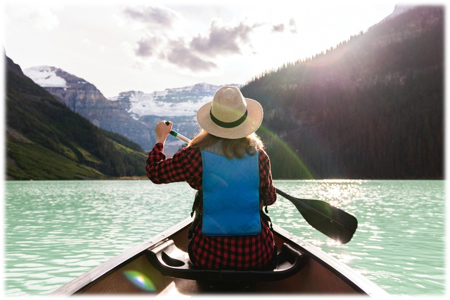 woman in canoe in lake with mountains