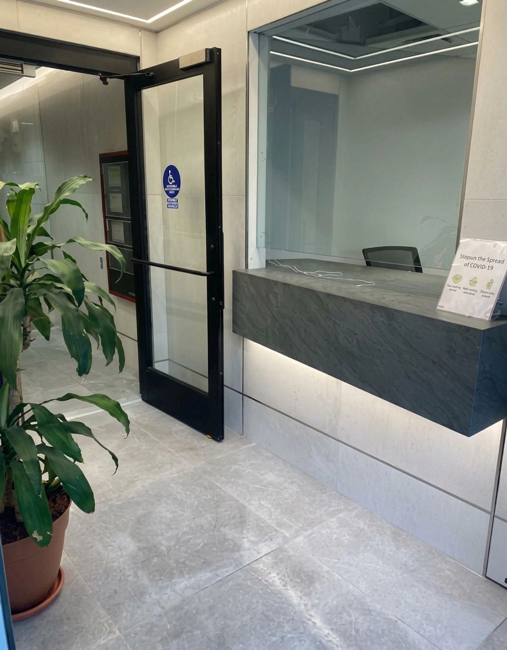 Modern reception area with a glass door and a plant.
