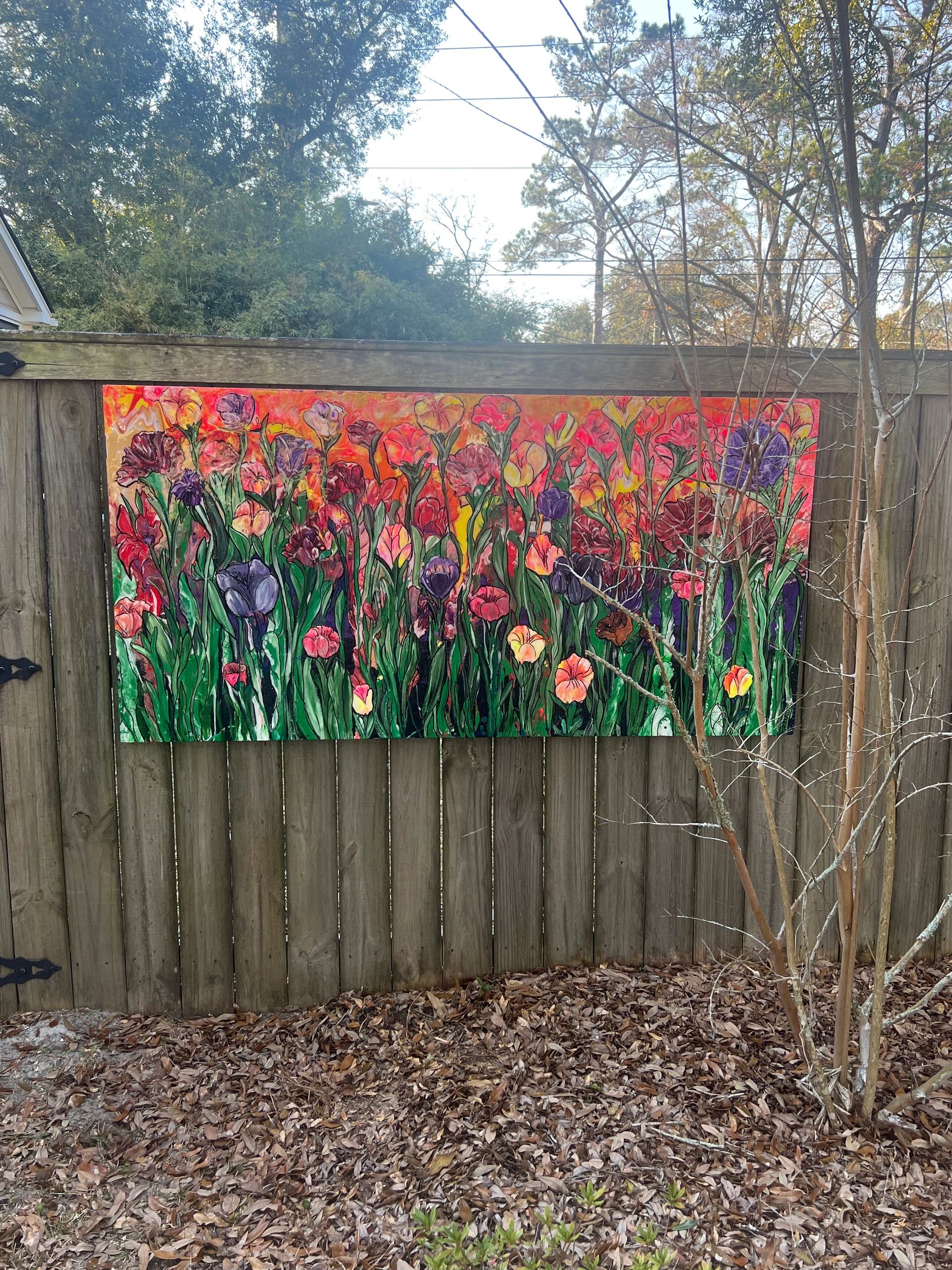 Colorful floral mural on a wooden fence outdoors.