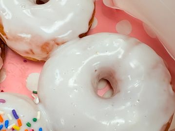 Close-up of a glazed white donut on a pink polka-dot plate.