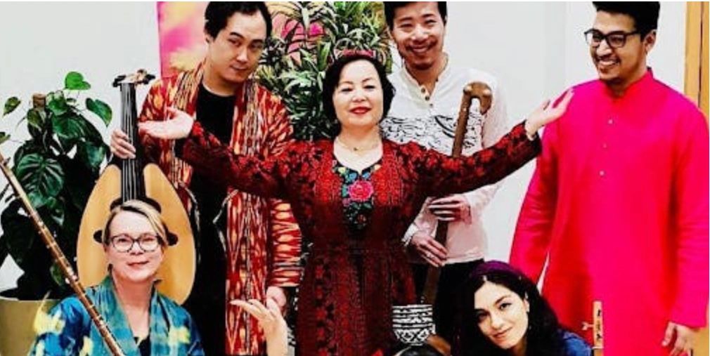 A diverse group of people in colorful traditional attire with musical instruments.