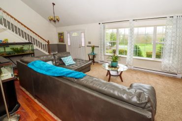 Bright living room with large windows and leather couches.