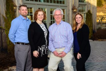 Group portrait of four adults standing outdoors.