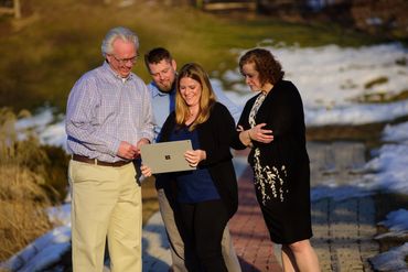 Four people looking at a laptop outdoors.