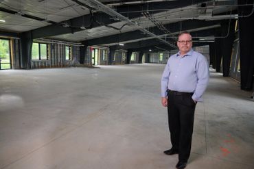 Man standing inside a large empty industrial building under construction.