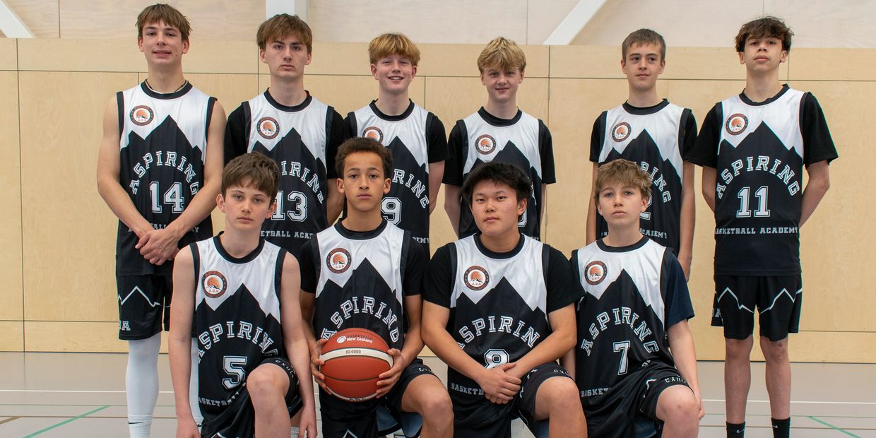 Youth basketball team posing in uniform indoors.
