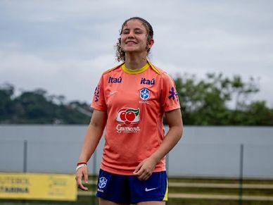 Young female soccer player smiling on the field in Brazil team gear.