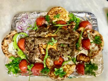 Izgara kebap ve garnitürlerle servis edilmiş lezzetli bir tabak.