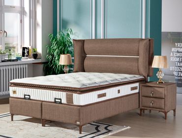 Elegant brown upholstered bed with a thick mattress in a bright bedroom.