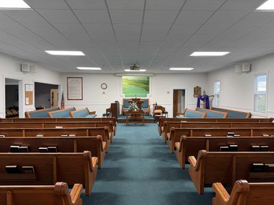 Interior of a small, simple church sanctuary with wooden pews and a pulpit.