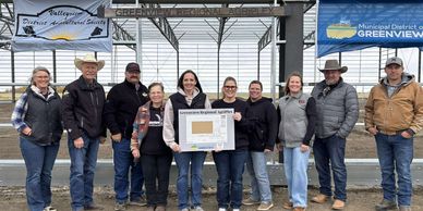 Group of people standing under a Greenview Regional AgriPlex sign.