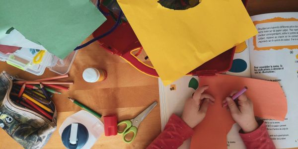 Child doing a craft project with colored paper and tools.
