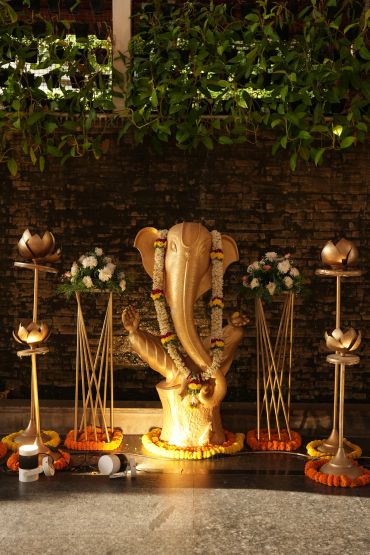 Golden statue of Lord Ganesha adorned with flowers.