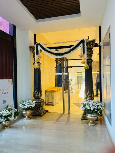 Decorated entrance with floral garlands and pots of white flowers.
