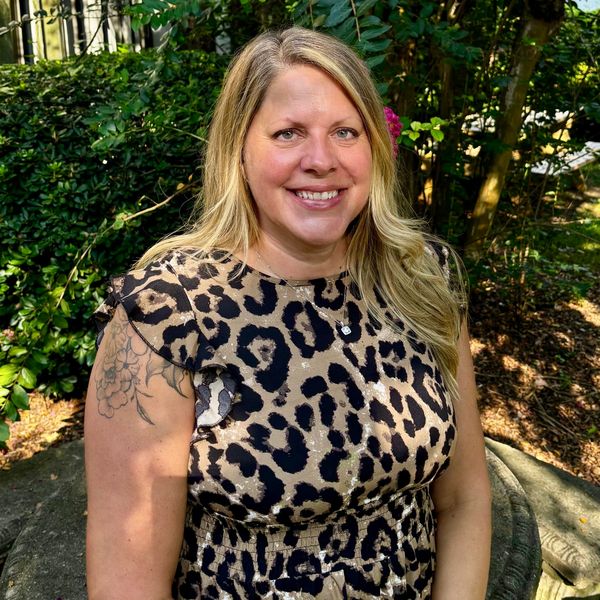 Smiling woman in leopard print dress outdoors.