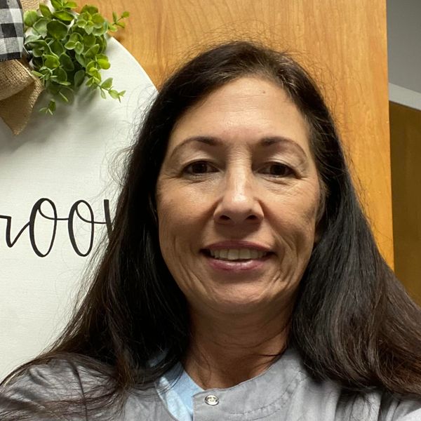 Woman with long dark hair smiling indoors.
